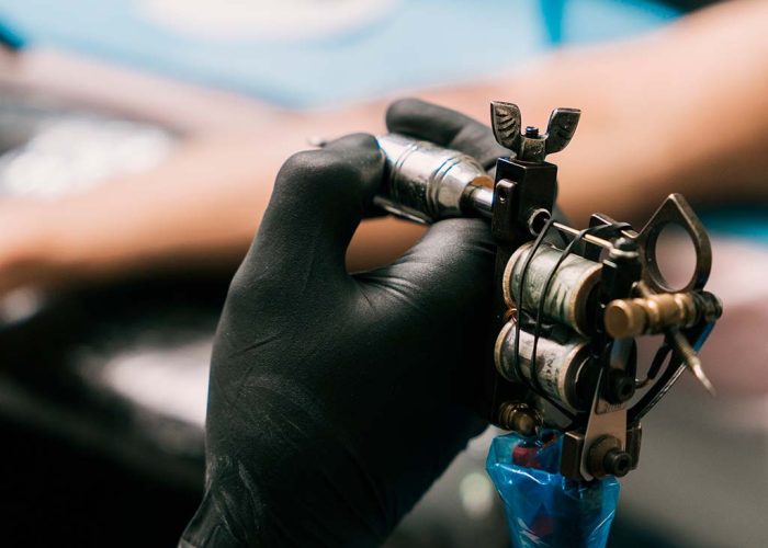 selective-focus-shot-hand-tattoo-artist-wearing-black-glove-holding-tattoo-gun selective-focus-shot-hand-tattoo-artist-wearing-black-glove-holding-tattoo-gun